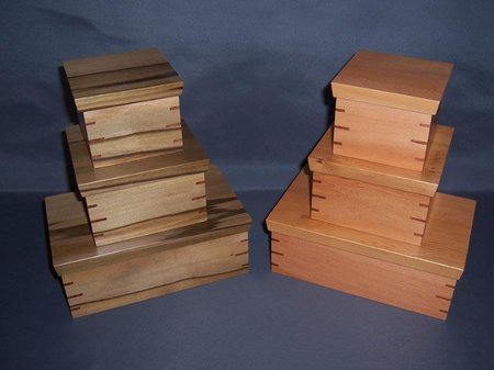 A photo of Peter Winskill's work. The photo shows 6 timbre boxes stacked from largest to smallest. The boxes are made with overlapping joints of different grains of wood and have a smooth and shiny finish. Image Peter Winskill.