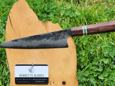 A hand forged knife by Justin Bennetts, resting on a Huon pine board
