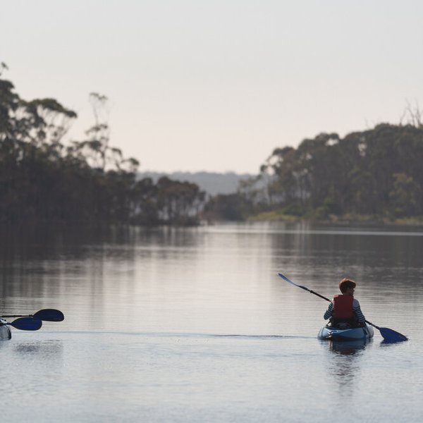 Kayak Orchestra. Three people in kayaks paddling through a long body of water. Credit Dylan Matorell.