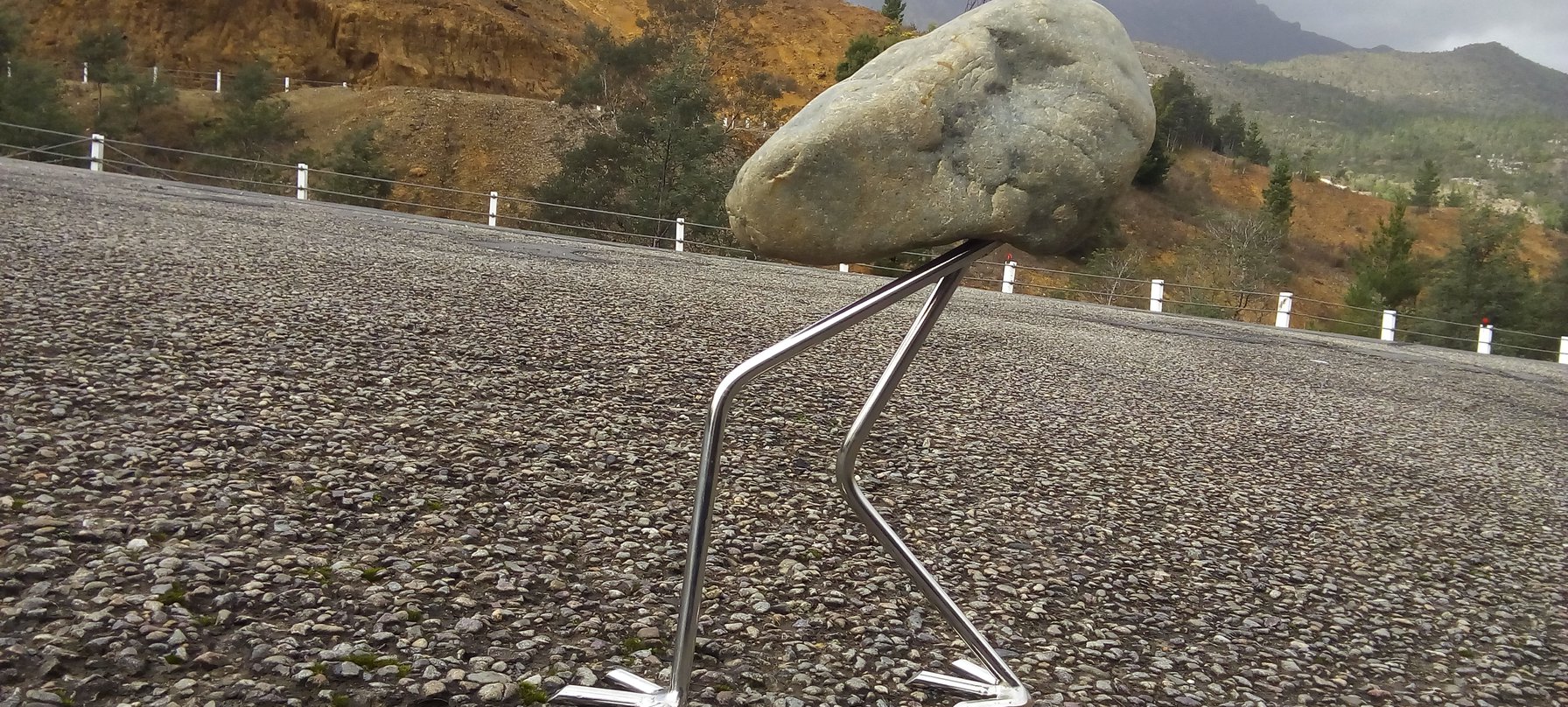 A photo of Colin Wilson's work - a small rock with metal legs is positioned to look as though is is walking up a hill. Credit Colin Wilson.