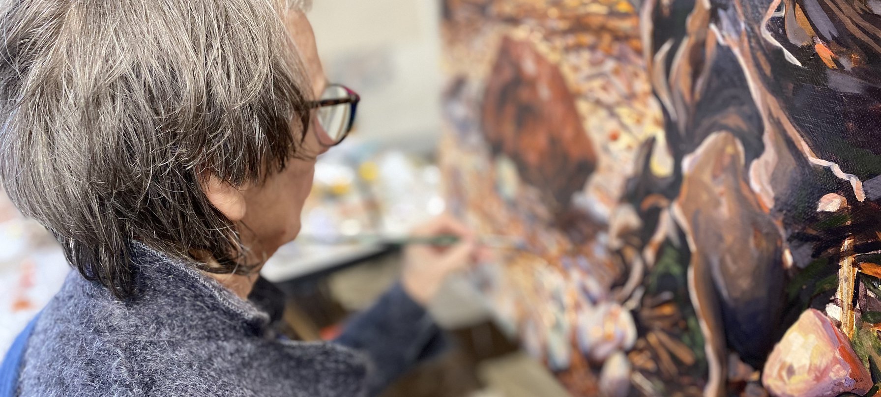 A photo of Helena Demczuk painting. The emerging painting features natural colours of browns, yellows, oranges and reds, creating geological-looking shapes. Credit Helena Demczuk.