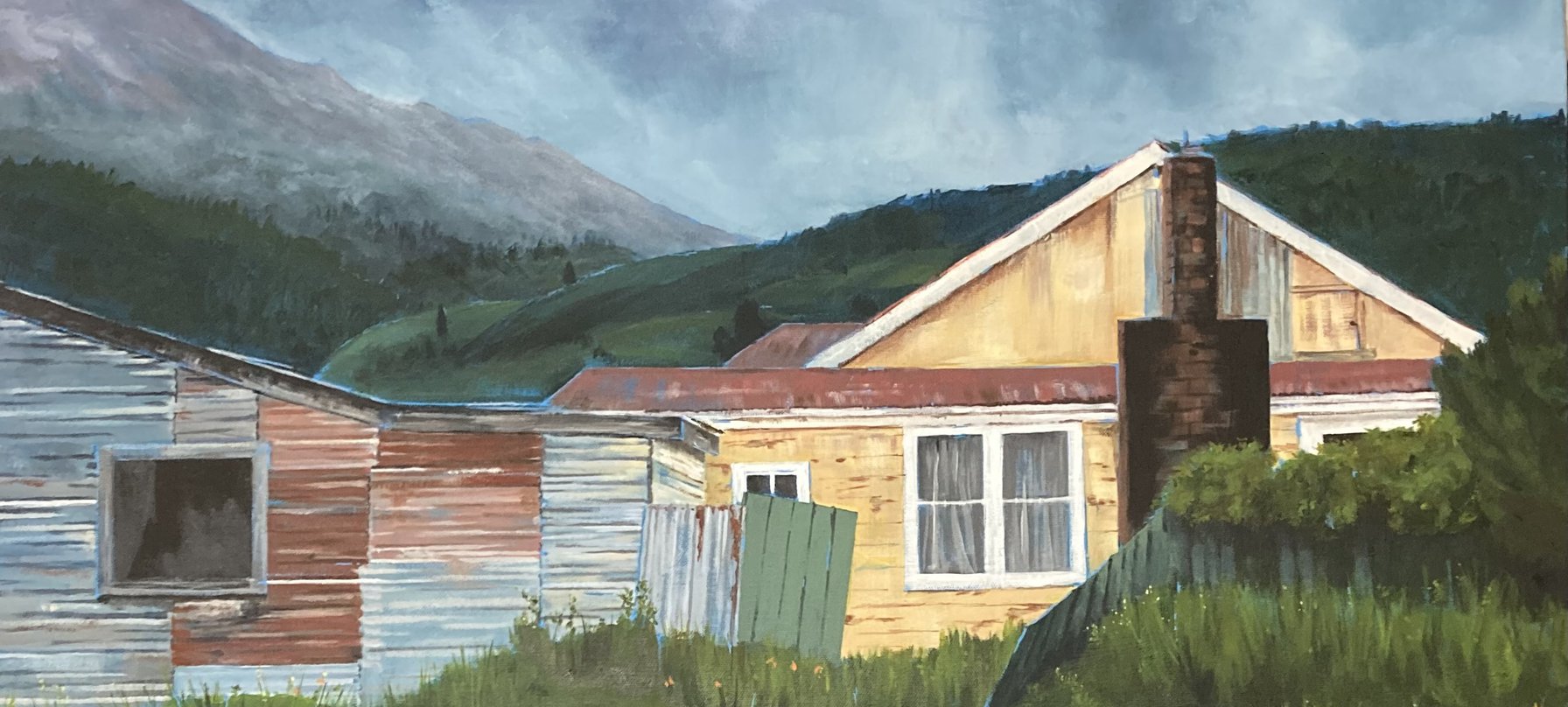 A cropped photo of Maxine Brown's painting, featuring a yellow weatherboard house and a tin shed below a murky blue sky and with a mountain in the distance. Credit Maxine Brown.