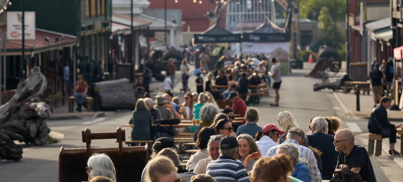 People sit at tables along Crib Road, a festival street party.