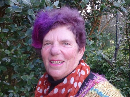 Ruth standing in front of a green shrub in the garden.