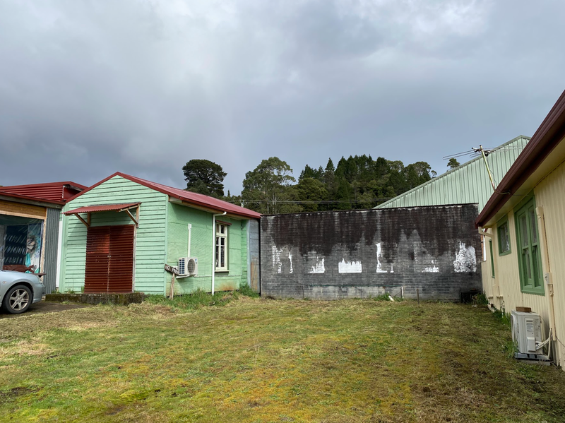 A photo of Little Orr Studio, a small mint-green weatherboard structure.