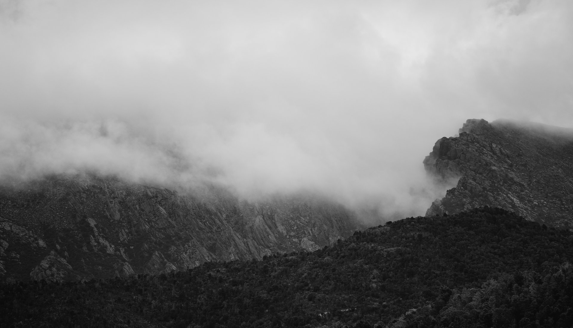 A black and white photo of the foggy mountain tops of Queenstown by Jesse Hunniford