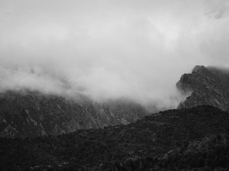 A black and white photo of the foggy mountain tops of Queenstown by Jesse Hunniford